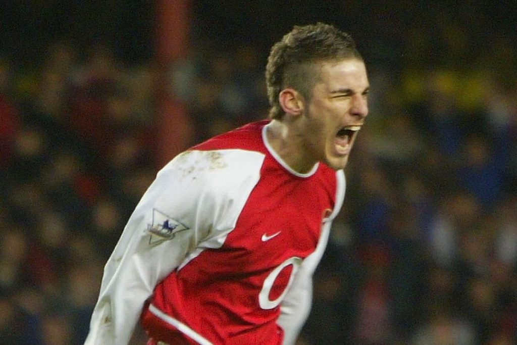 Former Arsenal midfielder David Bentley celebrating during a match in an Arsenal shirt.