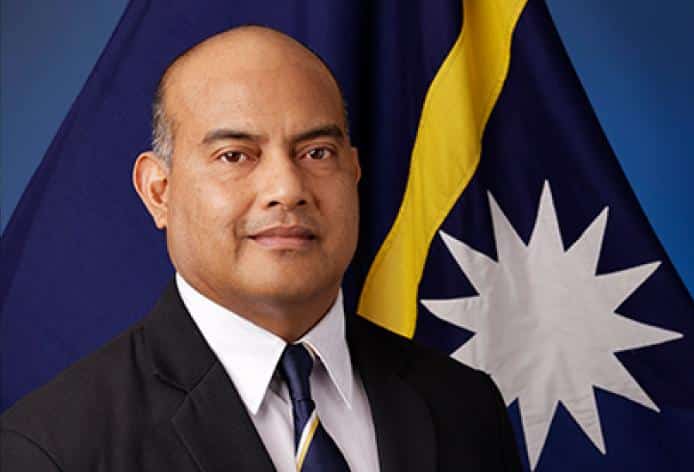 Official portrait of Naoero (formerly Nauru) President David Adeang wearing a dark suit and tie, standing in front of the national flag.