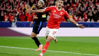 Benfica striker Vangelis Pavlidis celebrates a goal with arms outstretched during a match against Barcelona.