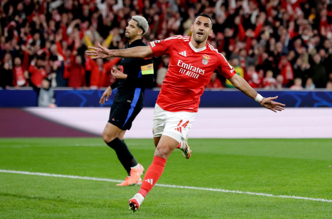 Benfica striker Vangelis Pavlidis celebrates a goal with arms outstretched during a match against Barcelona.