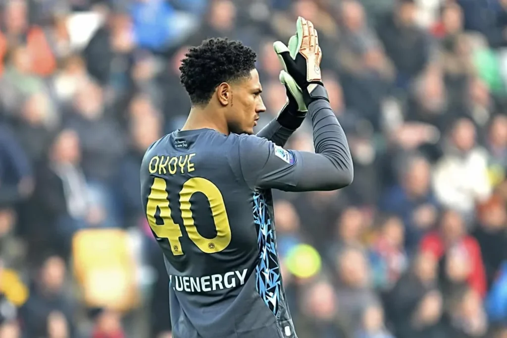 Maduka Okoye in Udinese goalkeeper jersey waving to fans inside a football stadium.